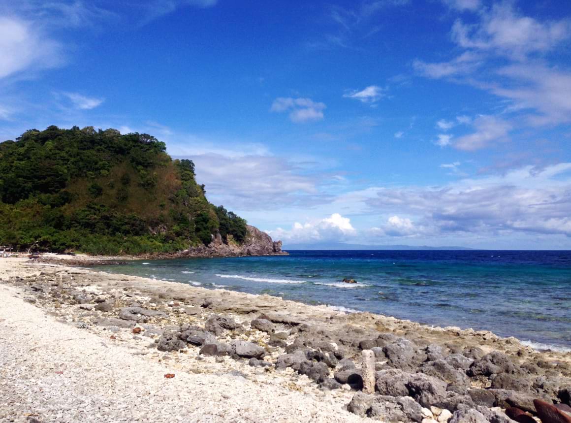 rocky beach on Apo Island Dumaguete with a mountain in the background