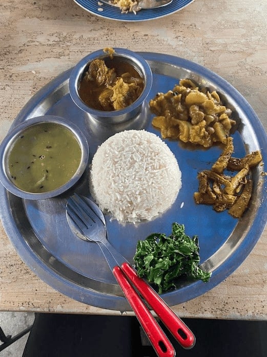 dal bhat and vegetables arranged on a circular tin plate in nepal