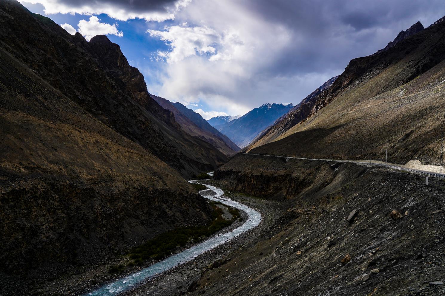 karakoram highway cutting through the massive tan mountains and rockface as seen while driving in pakistan