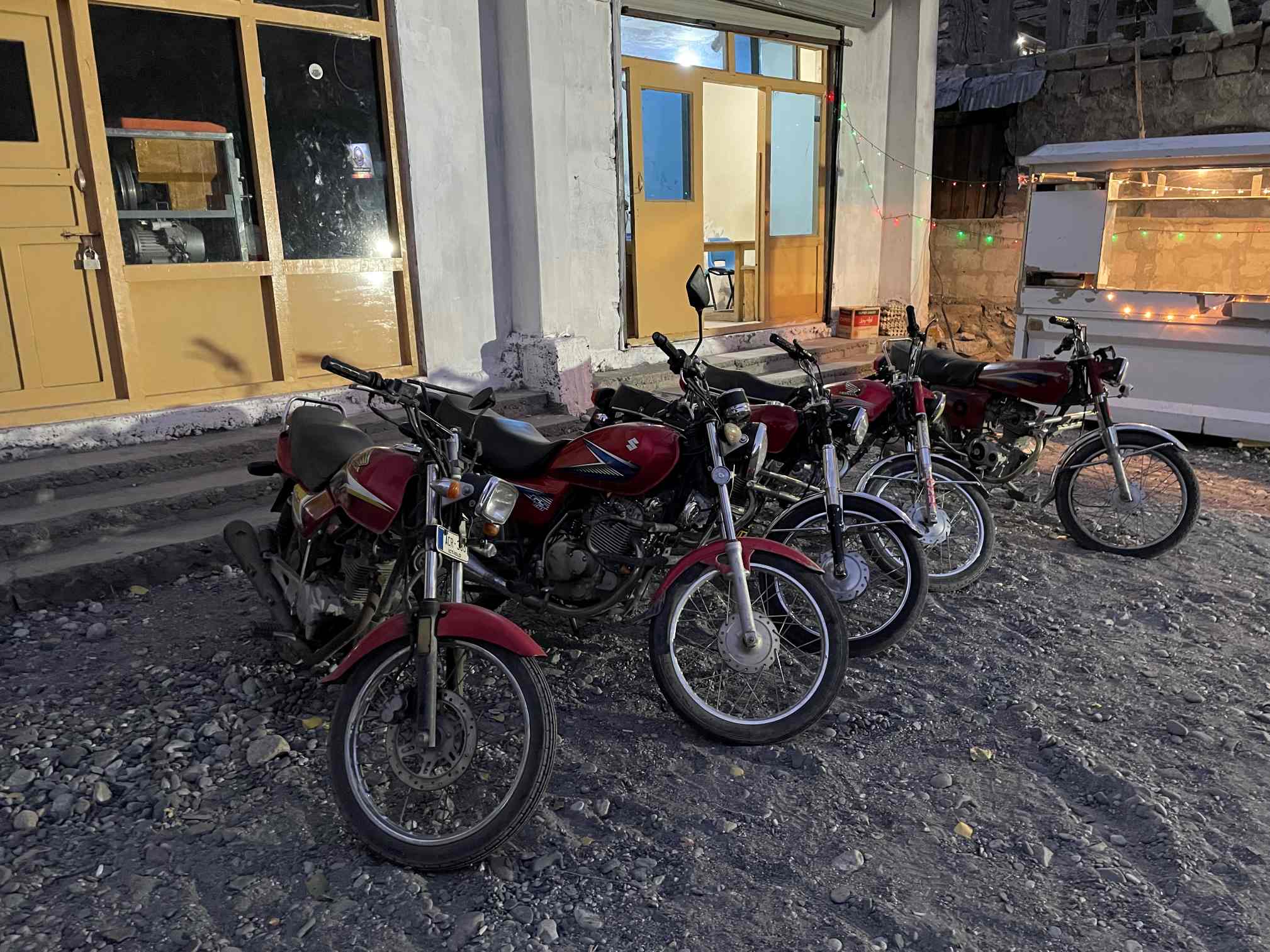 five red motorbikes lined up at a rental company in pakistan