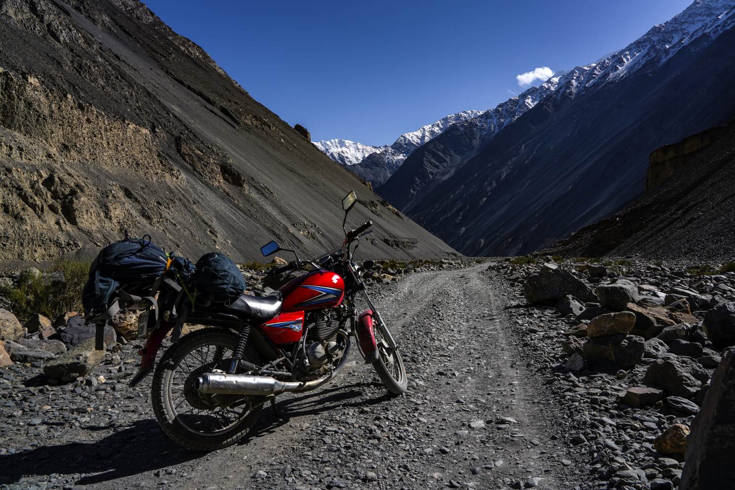red motorcycle on a gravel road filled with rocks heading toward shimshal valley in north pakistan