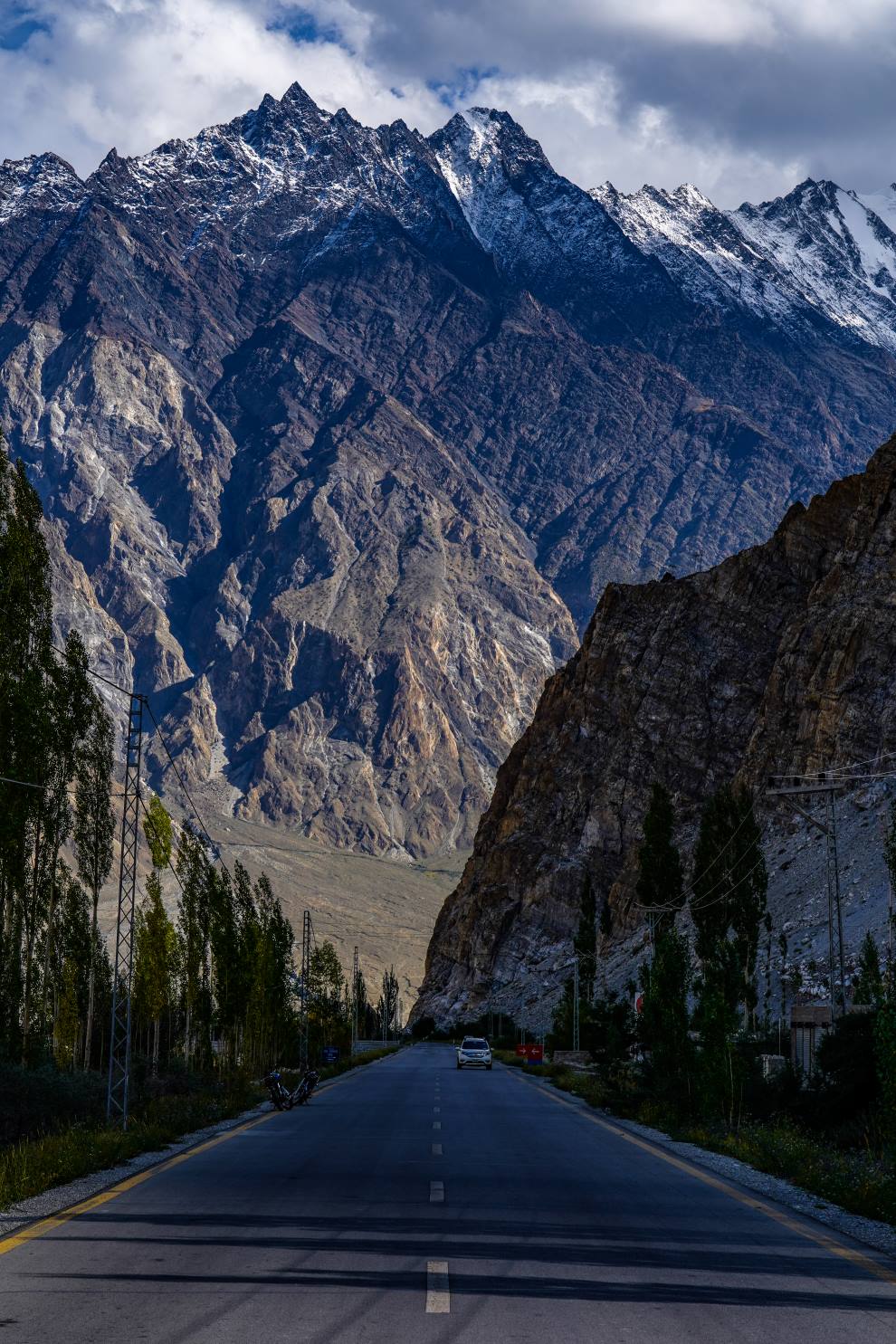 paved highway with a huge mountain rising above it in the distance in passu hunza valley pakistan