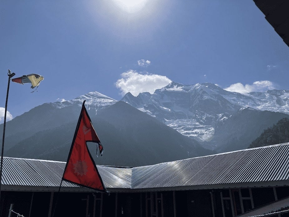 red and blue nepali flag with a big snow covered mountain in the background