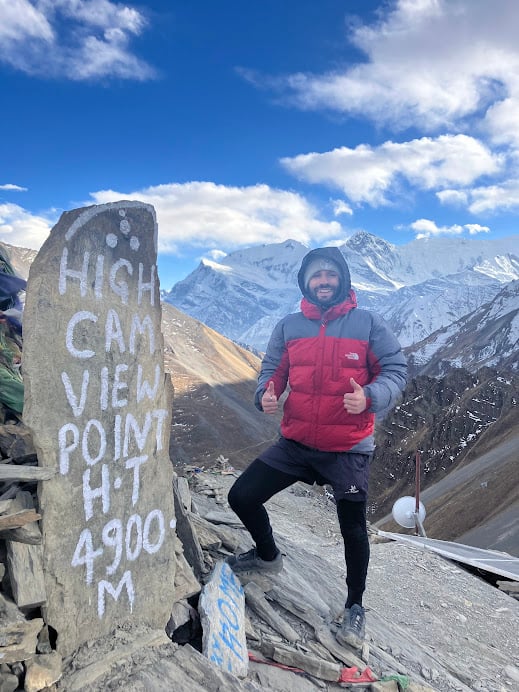 man standing at a trail marker sign in the high himalayan mountains of nepal