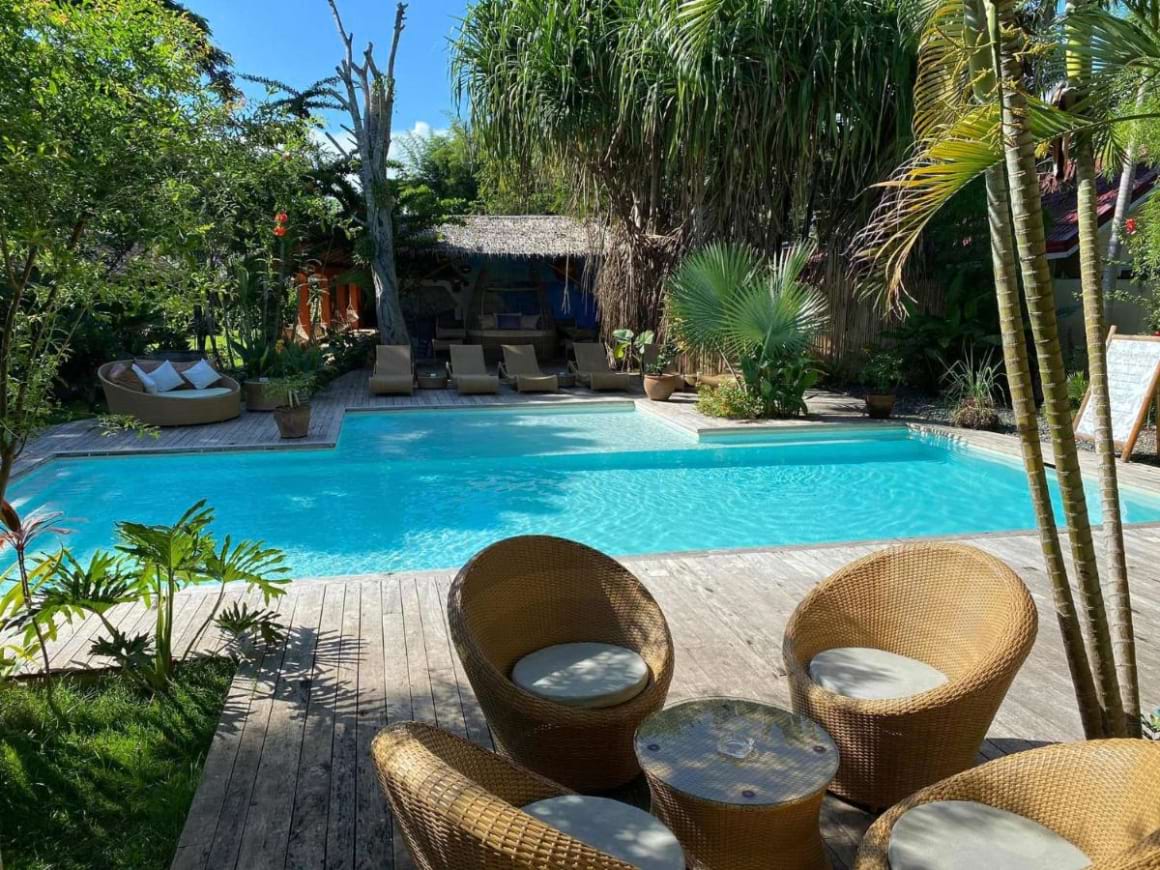 Pool with seating area surrounded by lush greenery in Hibiscus Garden Inn