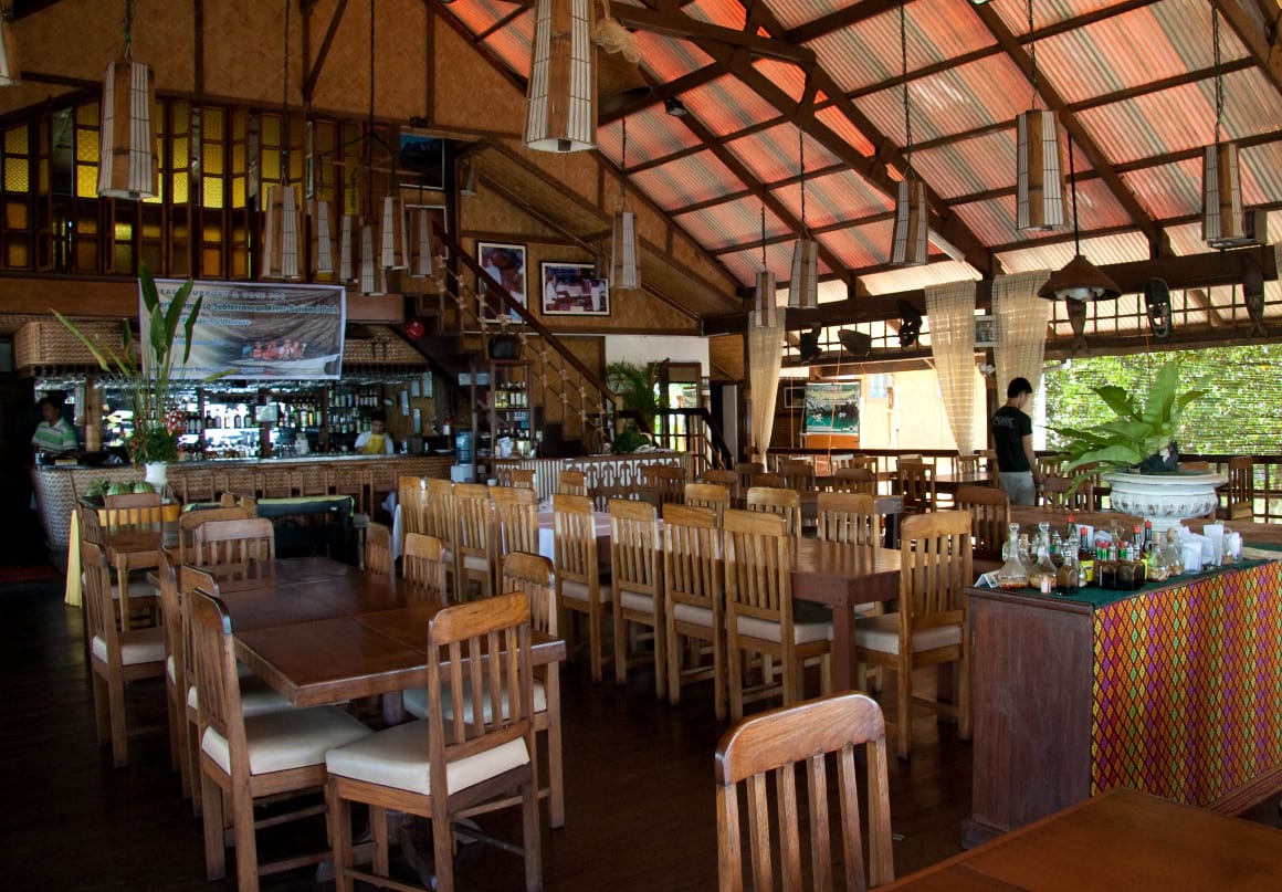 wooden tables and chairs under a wooden roof in Badjao Seafront Restaurant