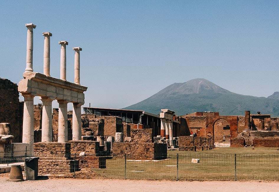 A view of the ruins of Pompeii with a volcano in the background in Italy