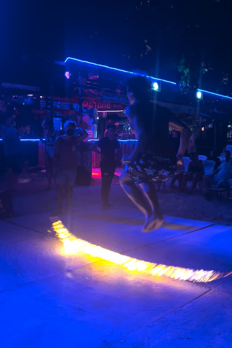 guy jumping over fire at a full moon party in thailand