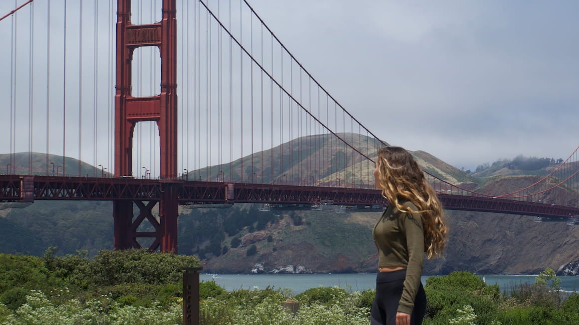 A girl looking off into the distance with a view of the Golden Gate Bridge in San Francisco, California