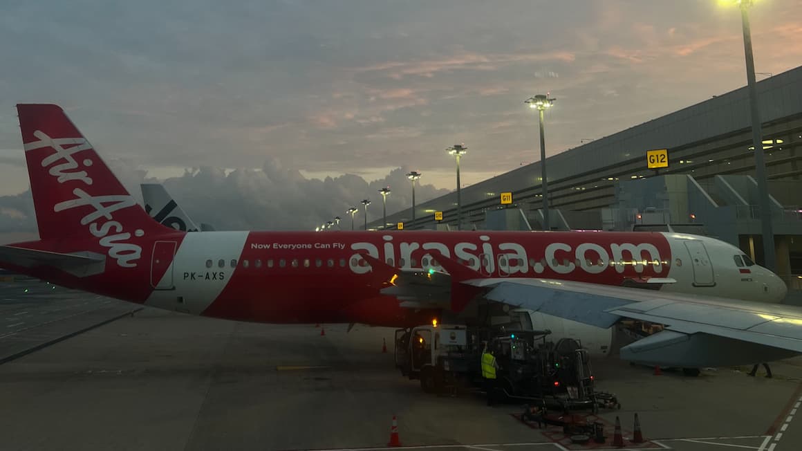 an air asia airplane at the airport with the sun setting in the background 