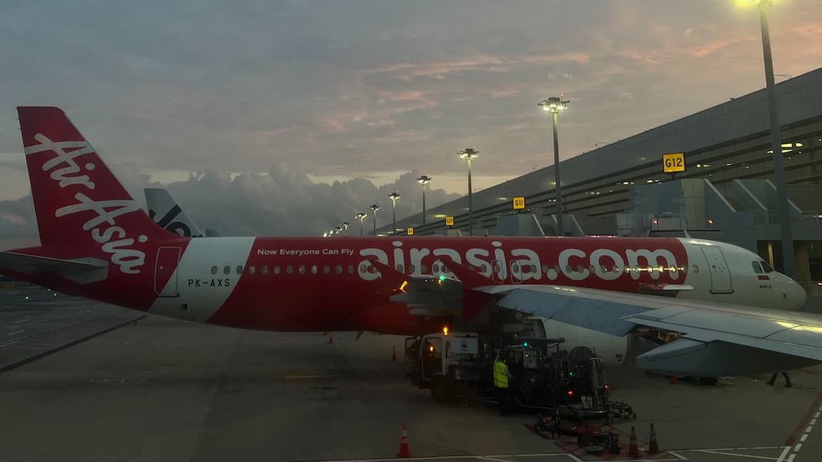 an air asia airplane at the airport with the sun setting in the background