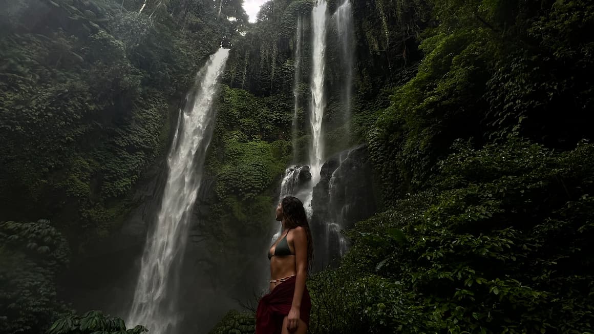 A girl standing near Sekumpul Waterfall in bali indonesia