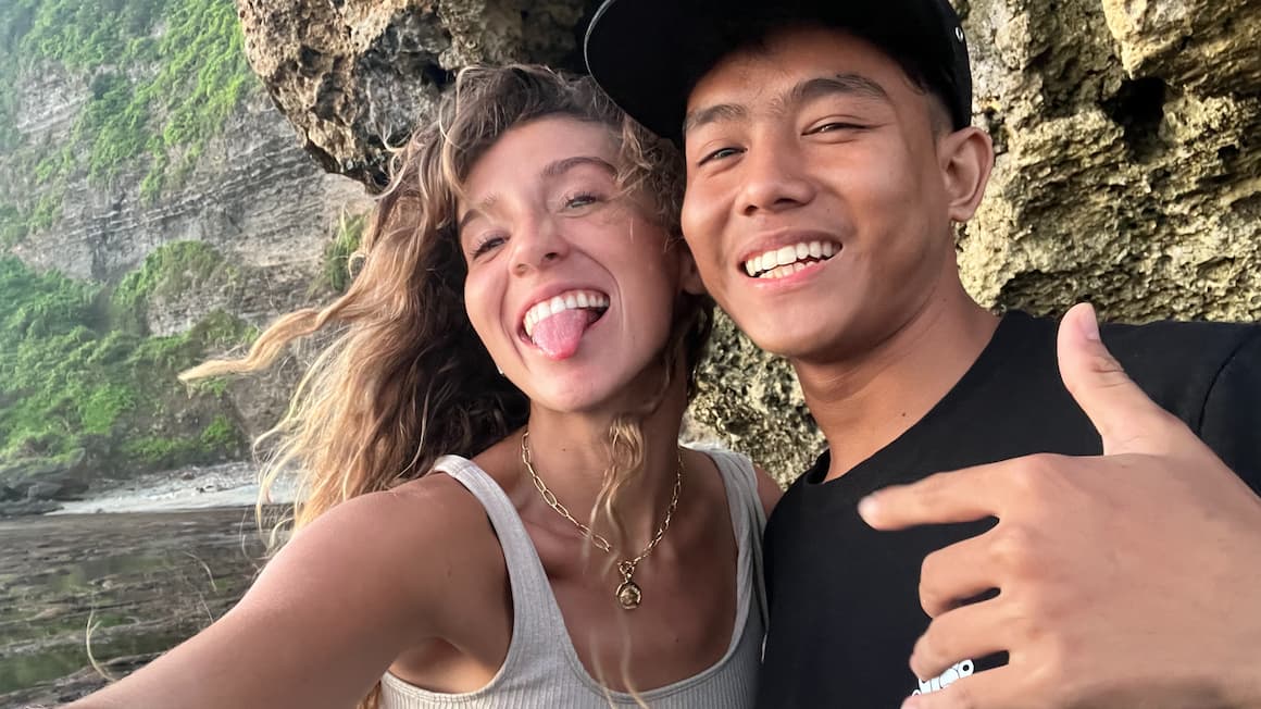 a girl smiling and making a silly face taking a selfie with a local in indonesia 