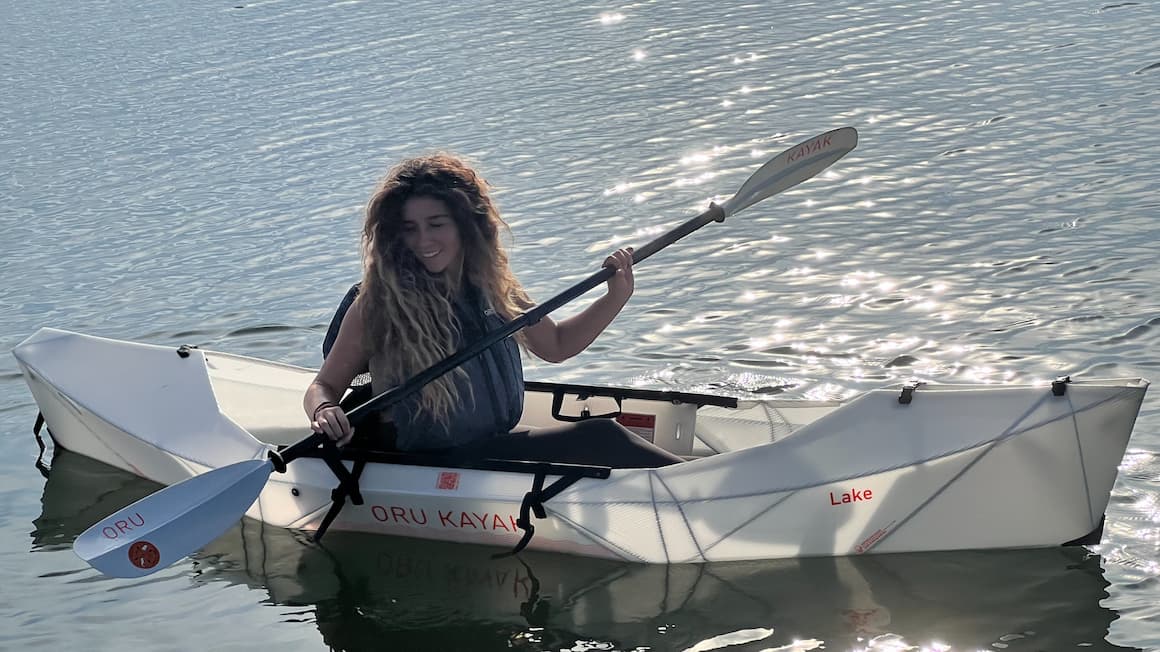 a girl kayaking solo on a still water lake