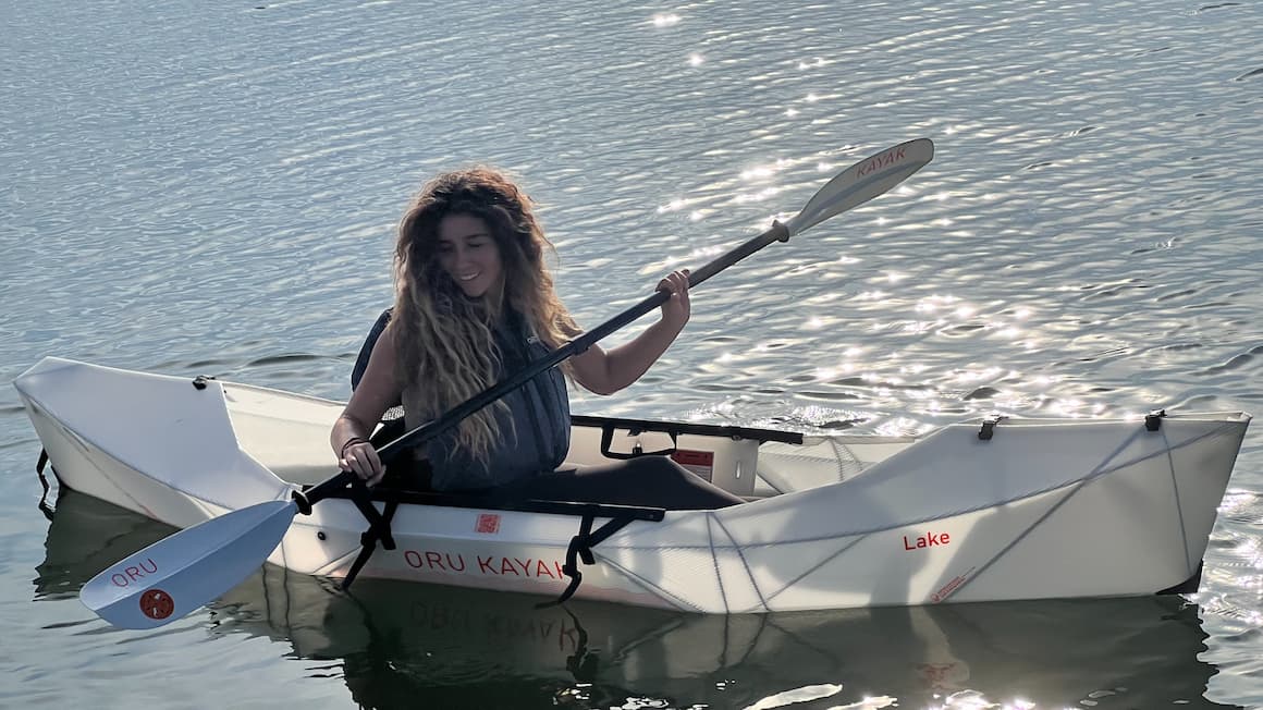 a girl kayaking solo on a still water lake 