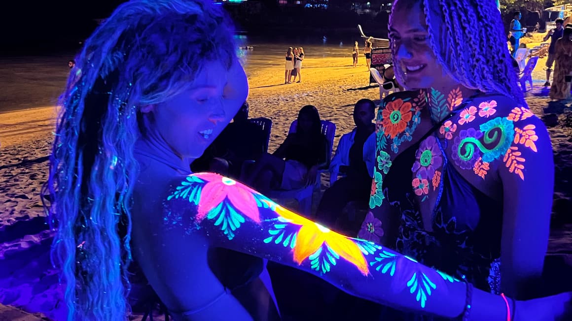 a girl and her friend covered in glow body paint art at a full moon party in thailand