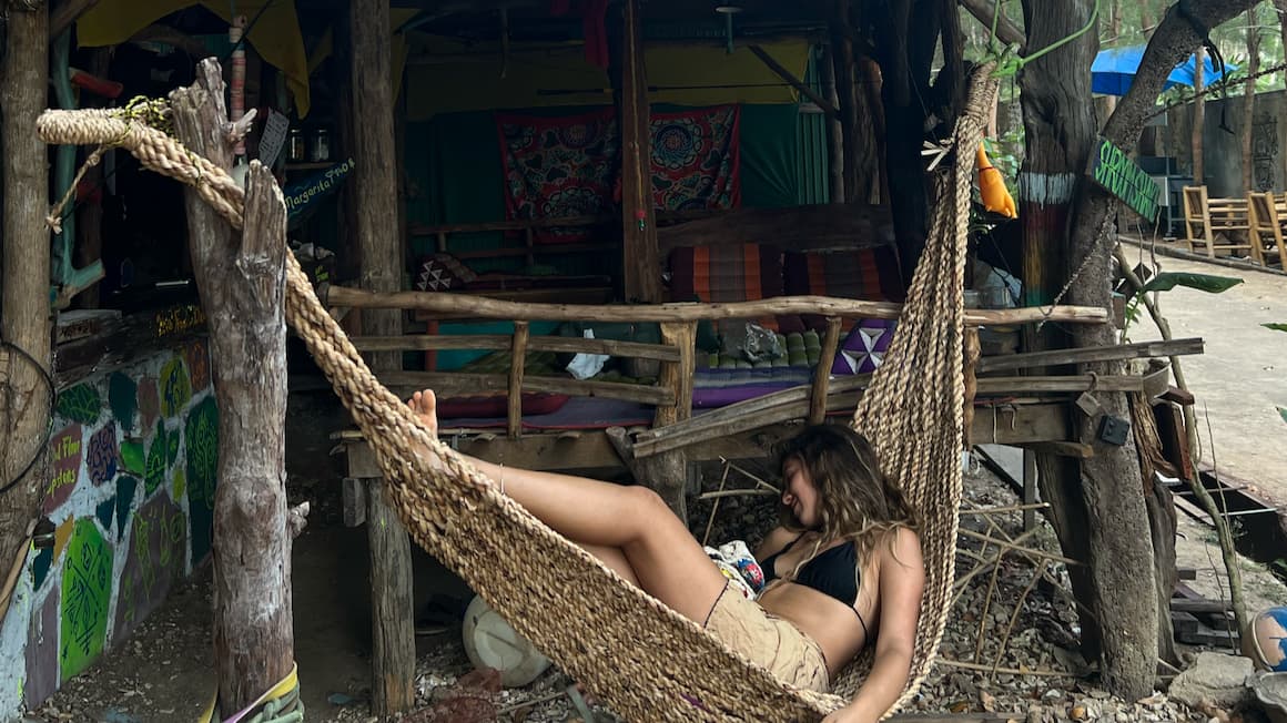 a girl sleeping in a hammock on a tropical beach in thailand