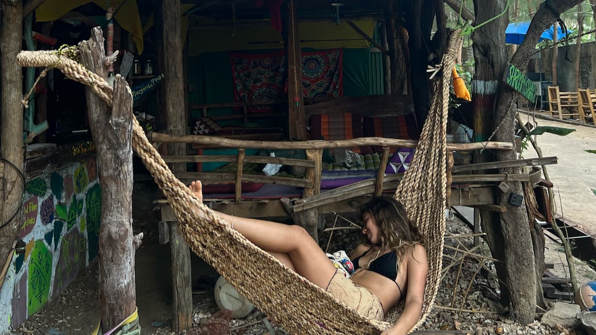 a girl sleeping in a hammock on a tropical beach in thailand 