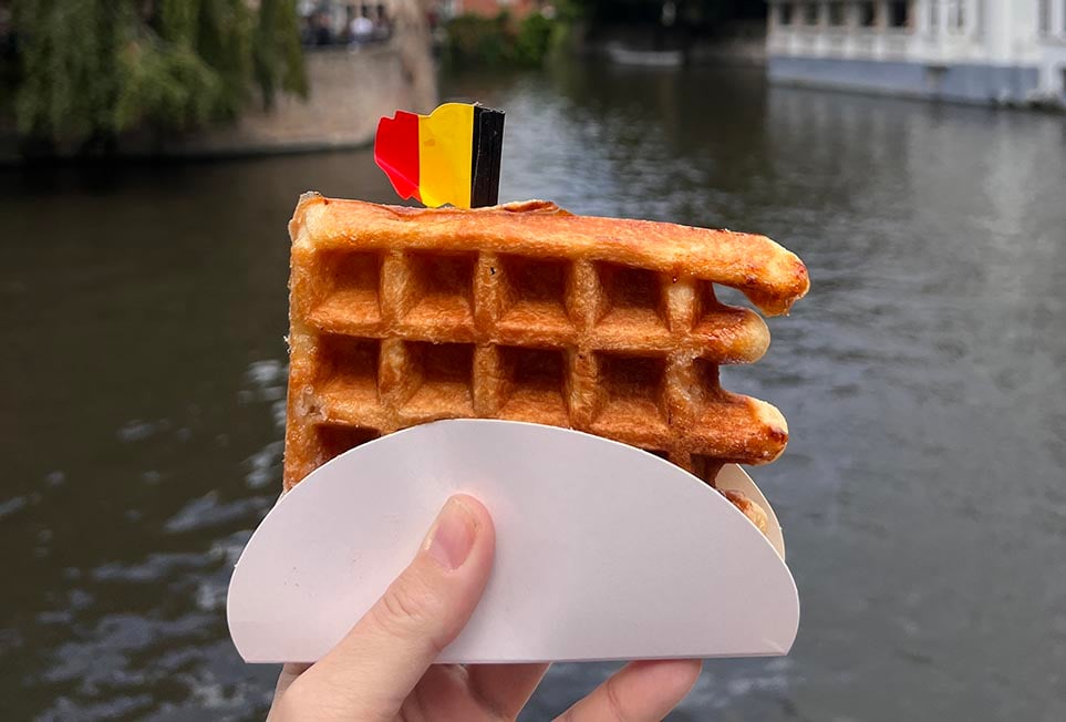 Holding up a waffle near a canal in Belgium