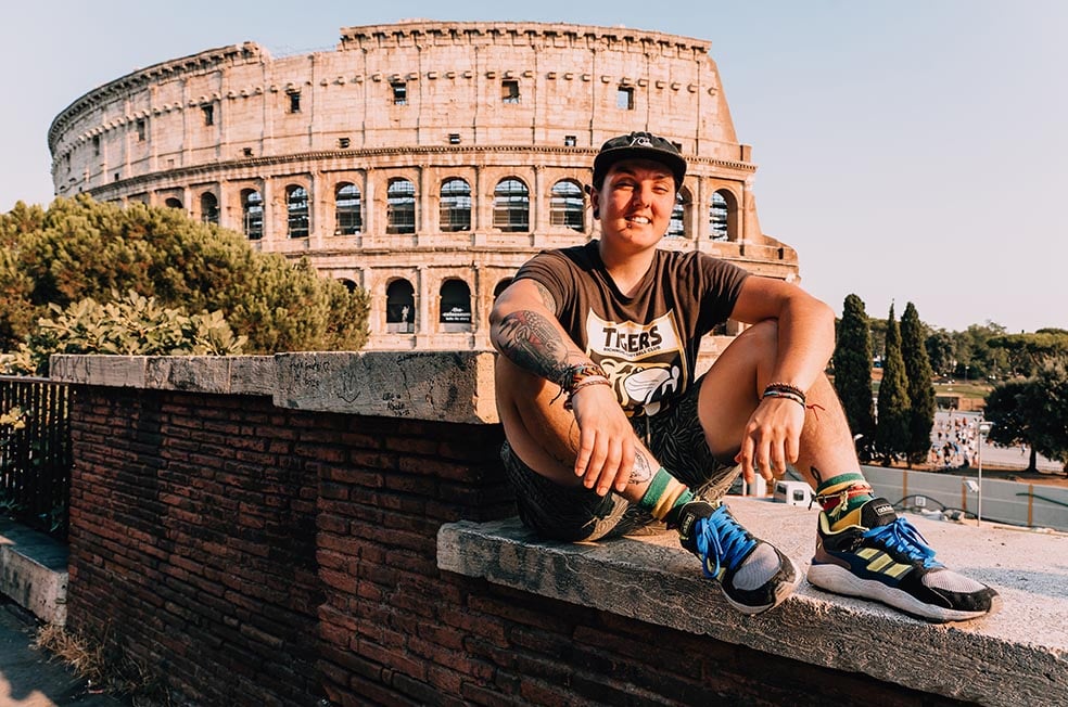 A person sat on a wall with the colosseum in the background in Rome, Italy