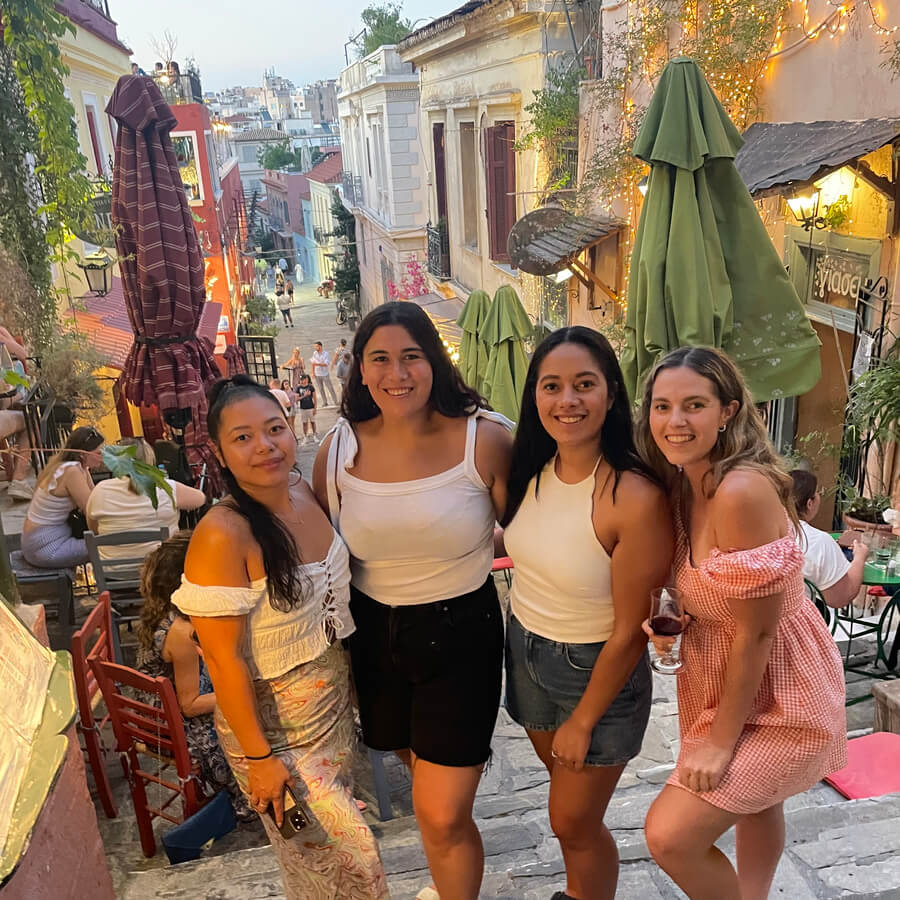 Four friends on the streets of Plaka surrounded by restaurants, lights and tress