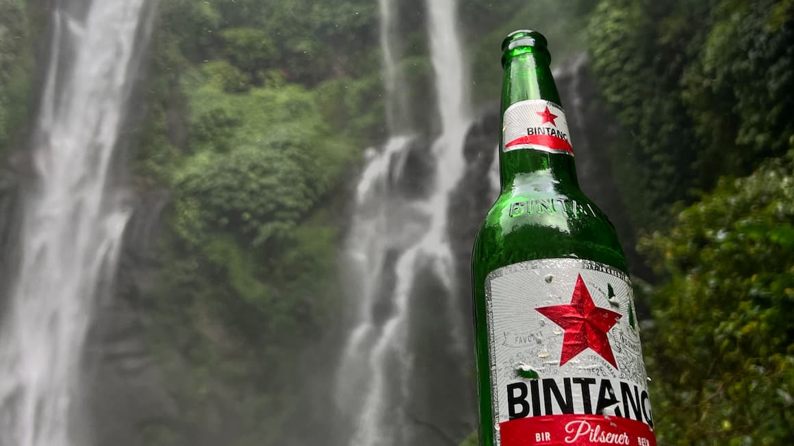 a bintang beer, with a waterfall in the background in indonesia