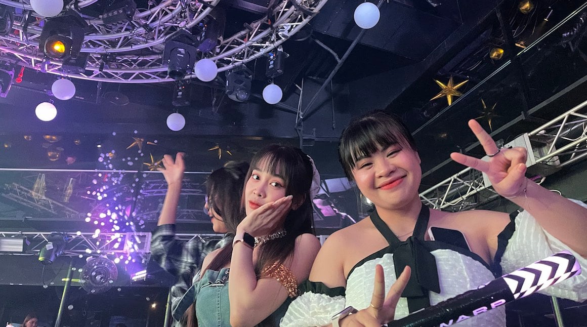 Two Japanese girls smiling for a photo in a club in Tokyo.