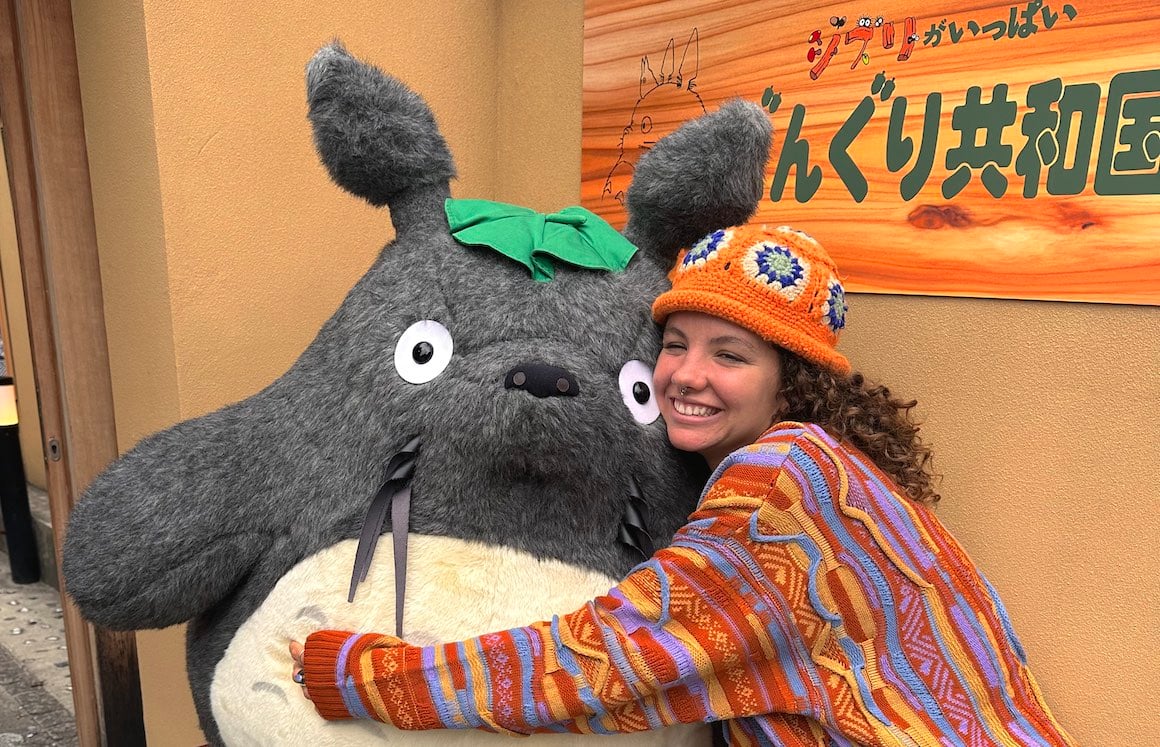 Girl hugs giant Totoro from the Studio Ghibli Film in Japan.