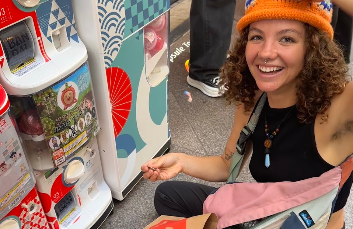 Girl gets toy from toy machine in Tokyo, Japan.