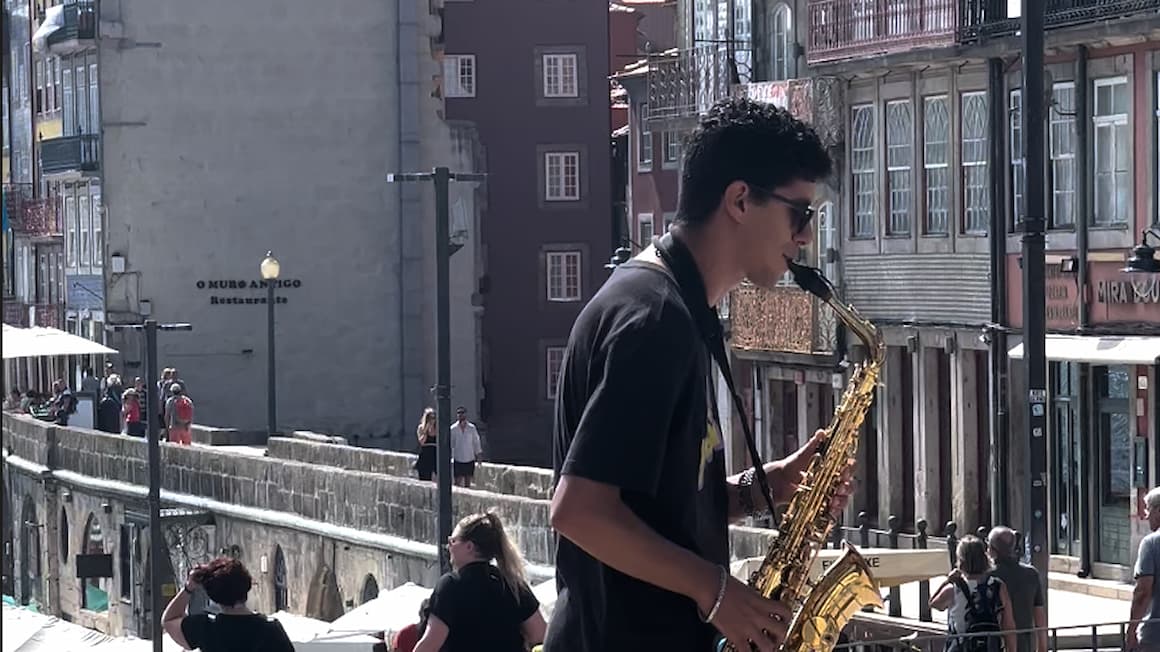 a guy playing the saxophone on the streets of porto 