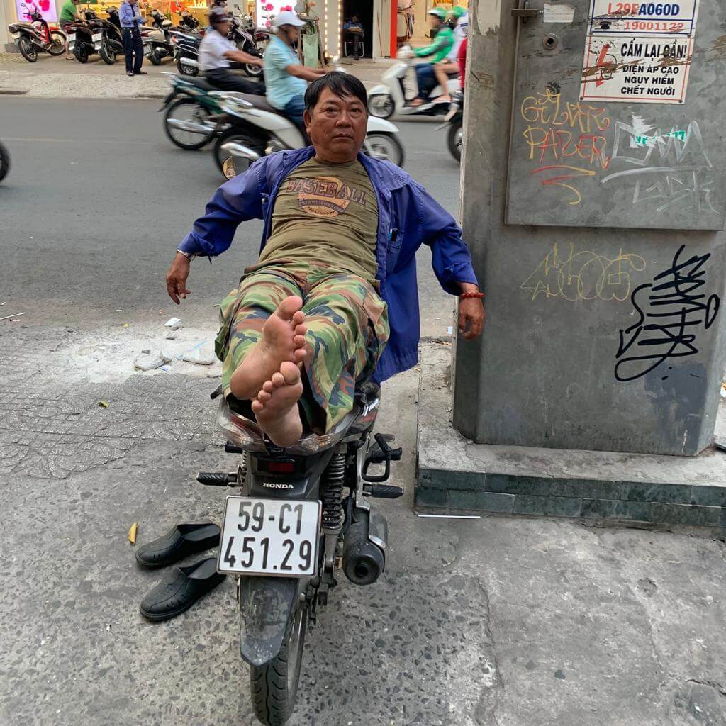 Man reclining on a bike in a Vietnam street.