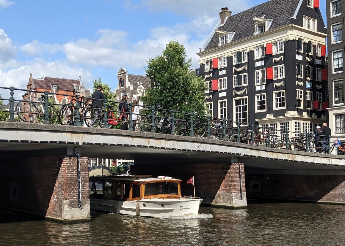 Canal boat going under a bridge in Amsterdam on a sunny day