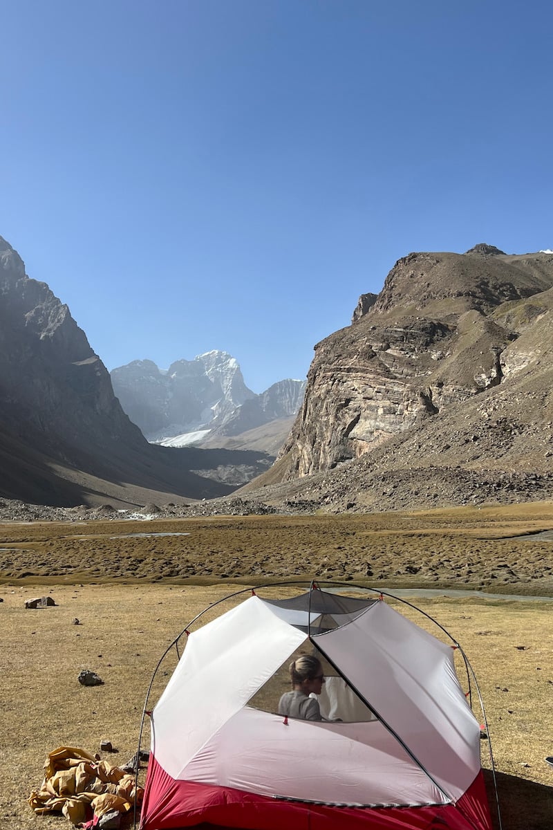 girl sitting in a msr hubba hubba 3 person tent while camping in front of a snow capped mountain in tajikistan central asia