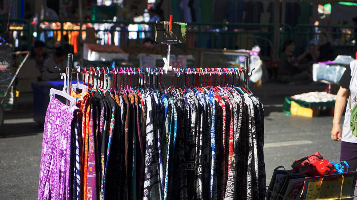 an array of colorful flowy elephant pants on a rack at an open air market in thailand