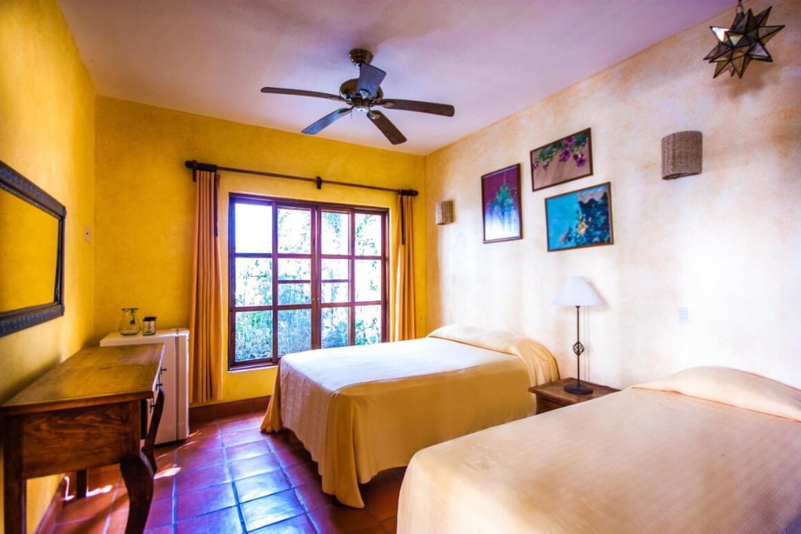 Double queen bed setup framed by a large window at Hotelito Los Sueños.  