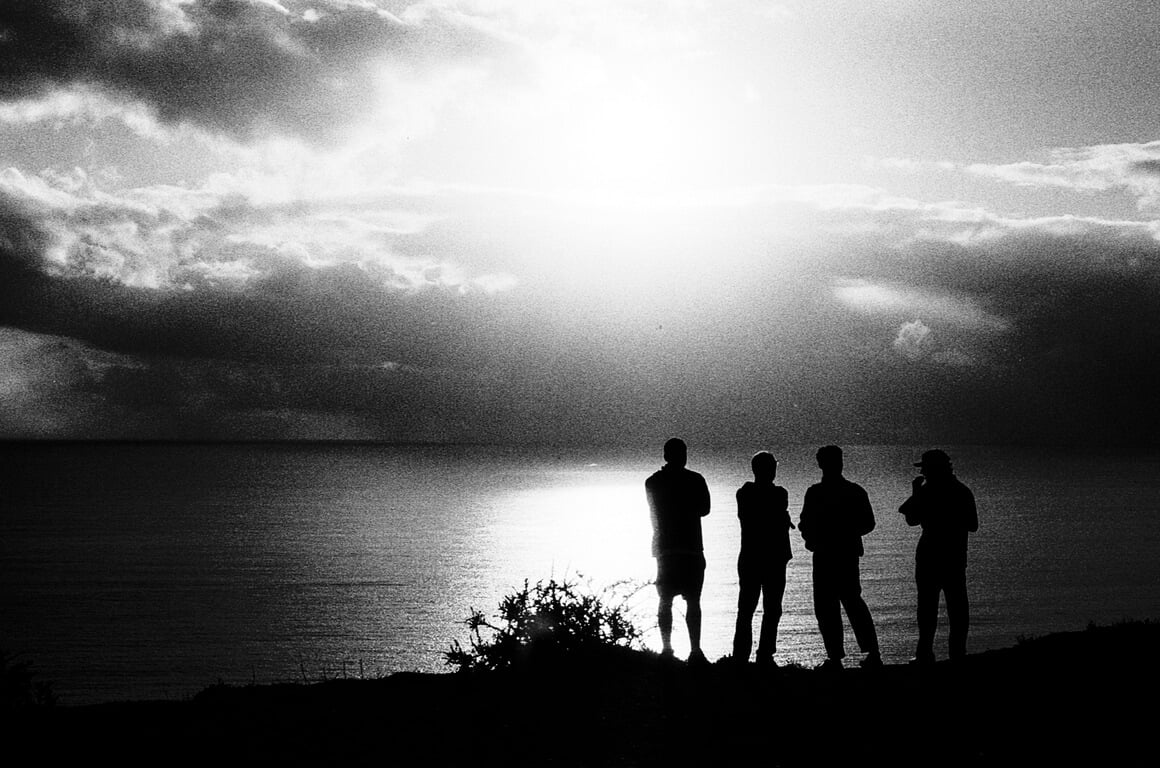 Four men watching sunset over the ocean in Portugal