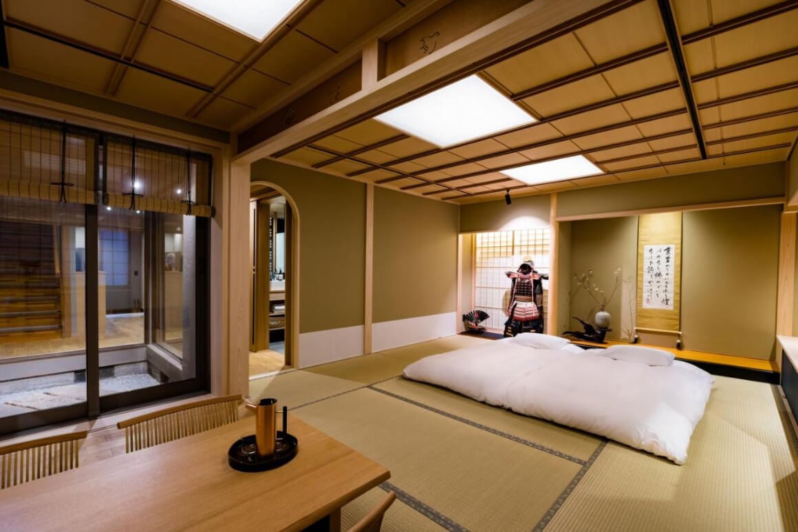 Room in a traditional Japanese inn (Ishibekoji Muan) with two futon beds and a small table with chairs.