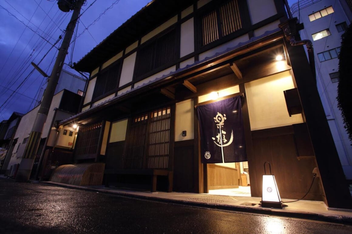 The front of a traditional Japanese Ryokan building (Luck You Kyoto ) at night softly lit