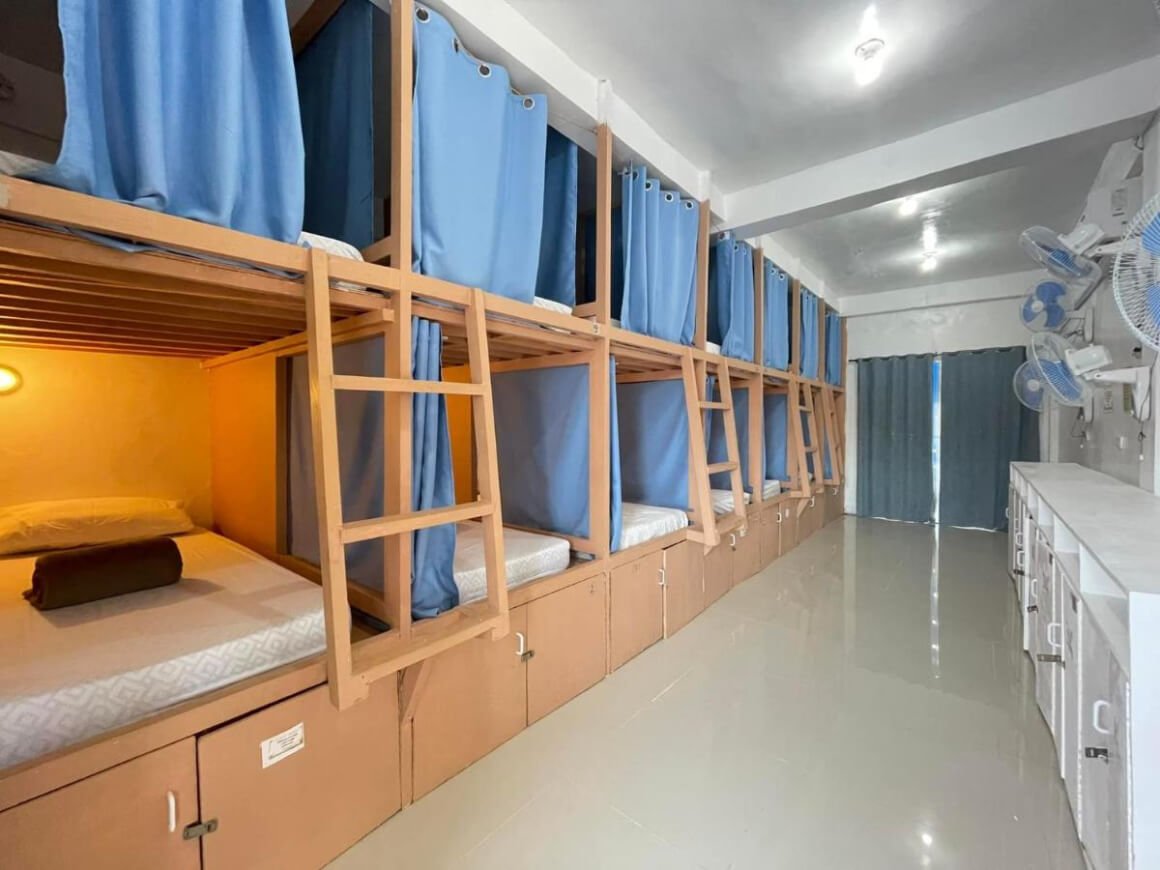 Wooden bunk beds with blue curtains in a dorm room in Malapascua Budget Inn