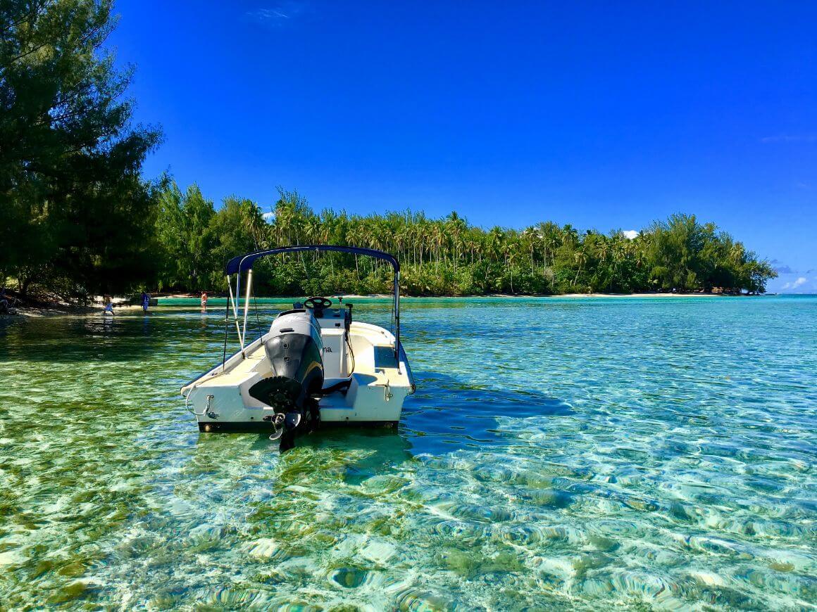 A white boat gliding on crystal-clear waters at Tiahura Beach, Moorea Islands