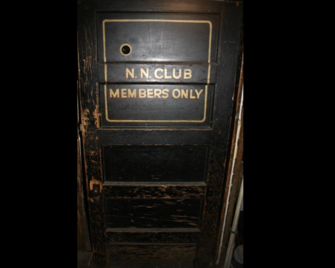 An old wooden door, painted black, with the inscription 'N.N Club Members Only'.