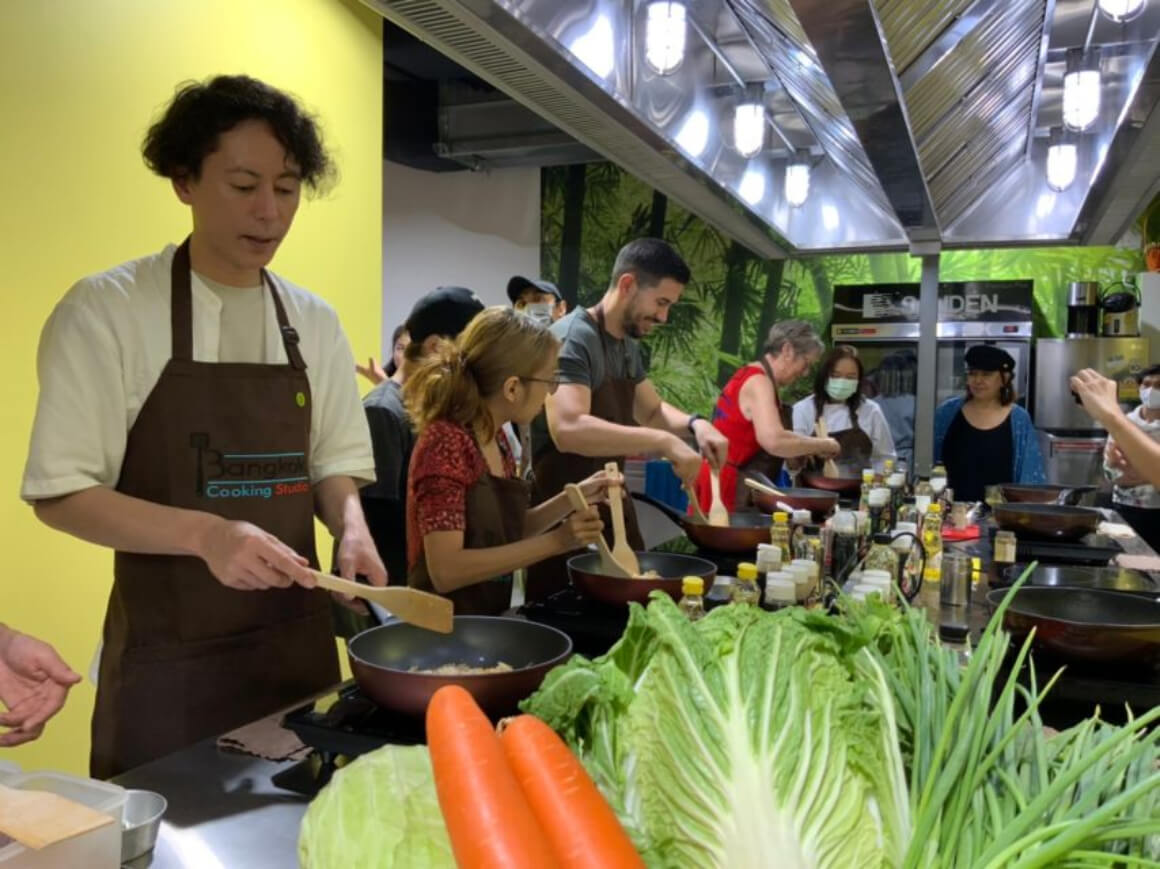 A group of people making their own dish in Bangkok cooking studio.
