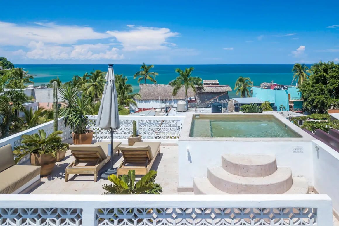 An Airbnb patio space with pool and lounge chairs overlooking the ocean in Sayulita