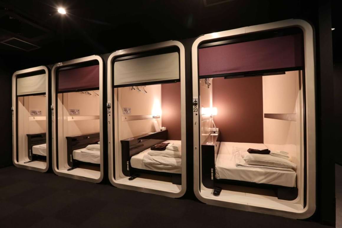 Large pod rooms with curtains and lighting arranged in rows in First Cabin Hakata