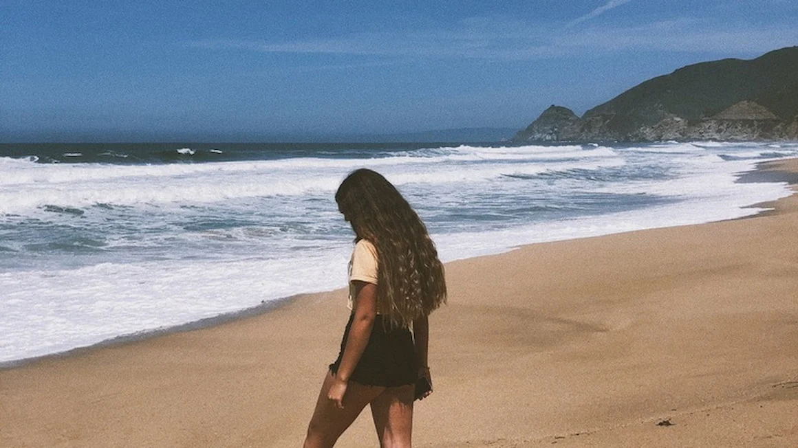 a girl walking on a sandy beach in California