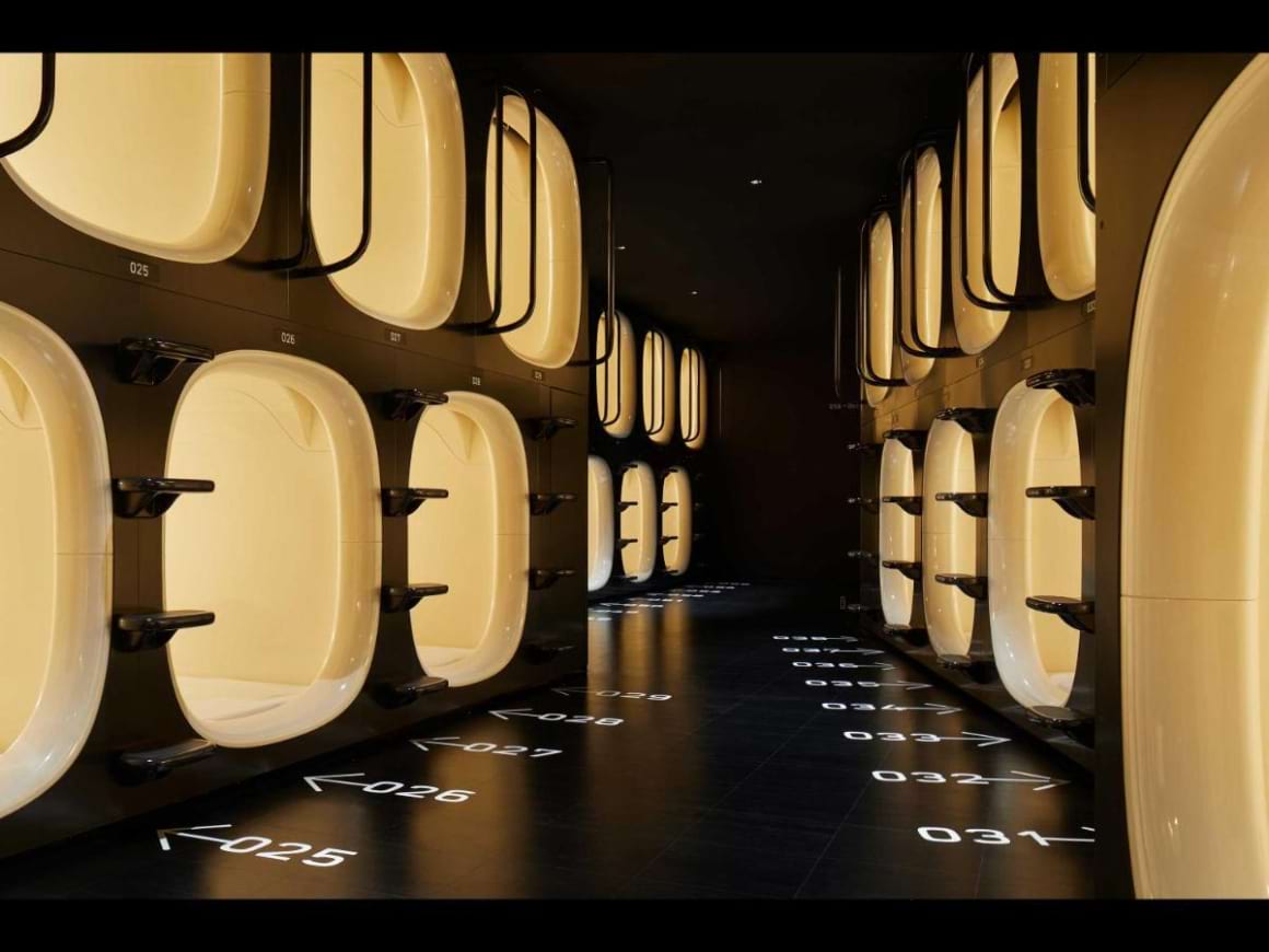 Two-level capsule rooms with yellow lighting down a hallway in nine hours Nakasukawabata Station