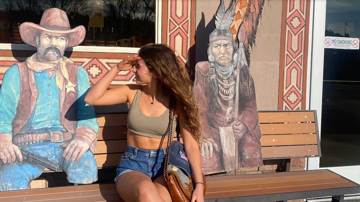 a girl looking at a cutout of a cowboy while sitting on a bench in Utah, USA United States of America.