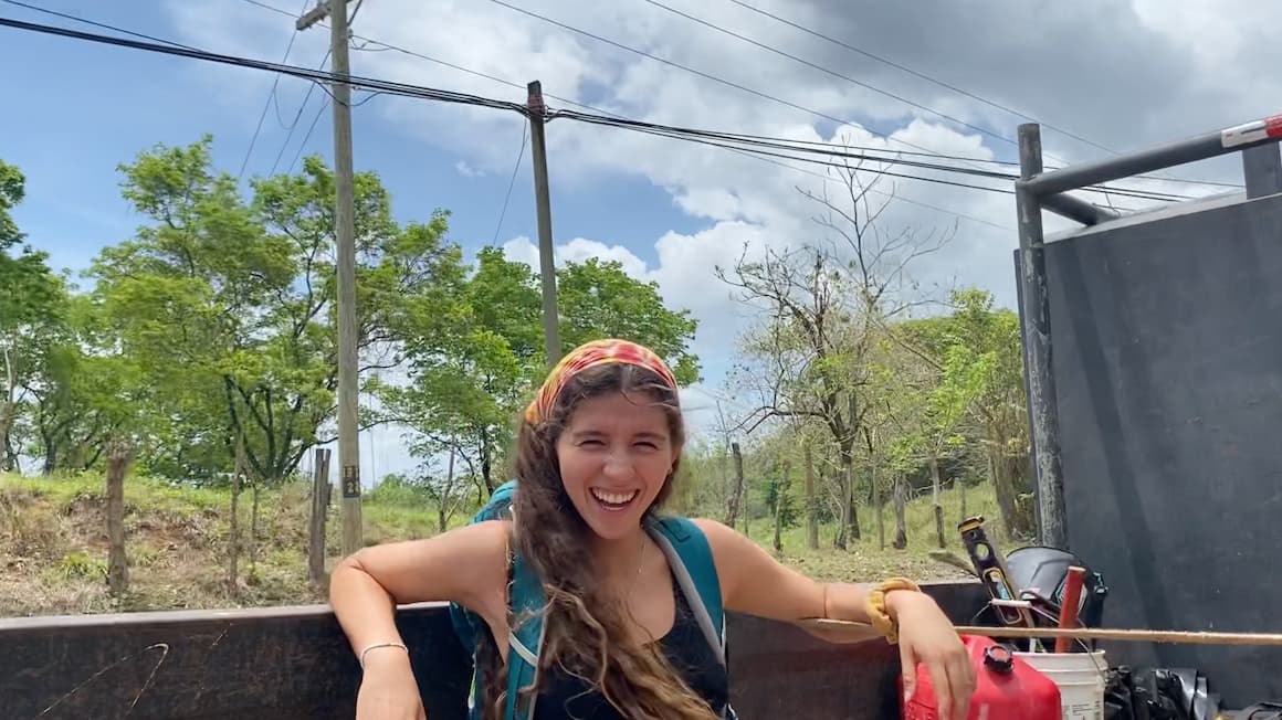 a girl hitchhiking in the back of a truck while traveling through costa rica