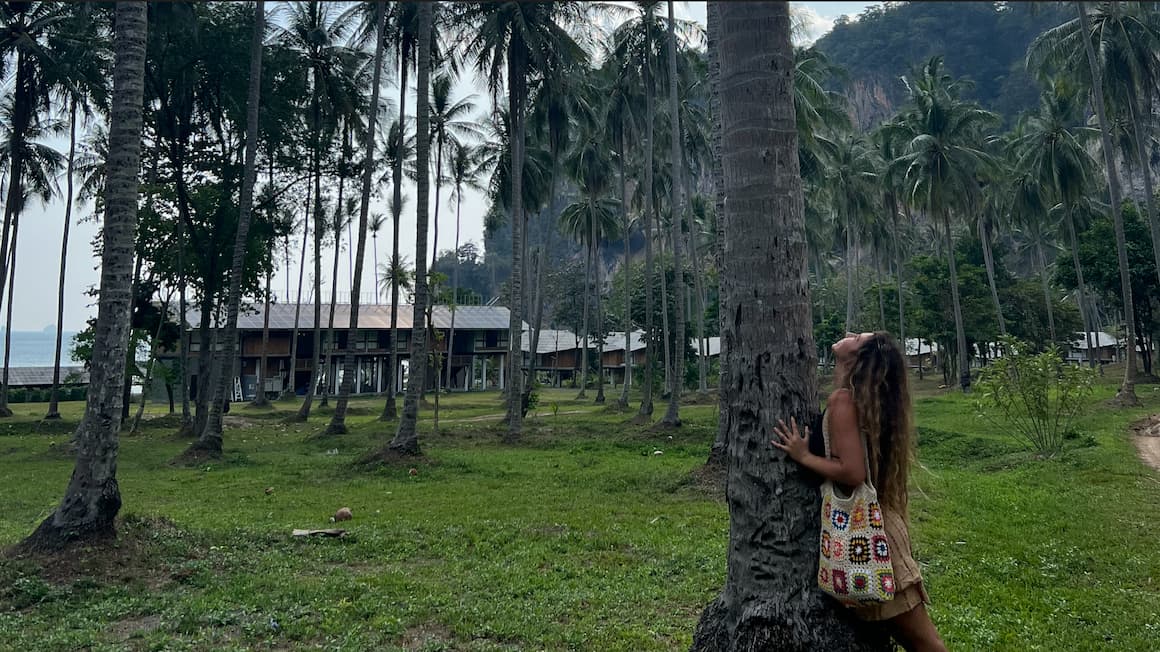 a girl hugging a palm tree in a field full of palm trees in Thailand 