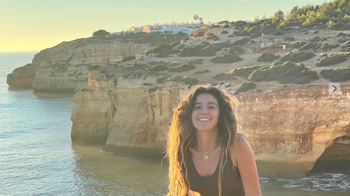 a girl smiling in front of scenic cliffs and the ocean of lagos,portugal 
